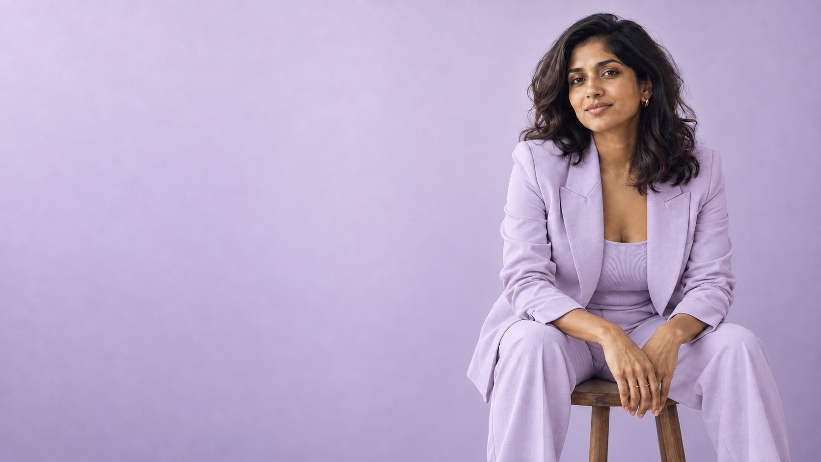 Entrepreneur in lavender clothing against a lighter matching pastel backdrop, with fine film grain